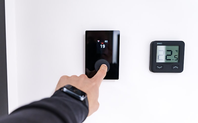 Finger adjusting a modern digital thermostat